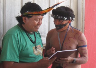 Marcelo (a la derecha) alcanza a Davi Kopenawa el libro Wayamou.