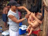 Ein Yanomami-Krankenpfleger impft eine Mutter.